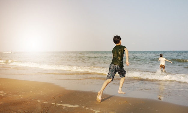 Dzieci biegają na plaży w promieniach słońca.