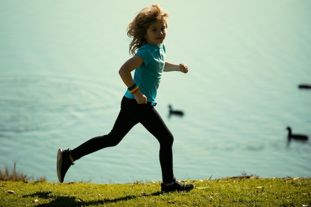 Zdjęcie dzieci biegające na świeżym powietrzu biegaj i zdrowy sport dla dzieci dziecko biegające na letnim polu w pobliżu jeziora kid