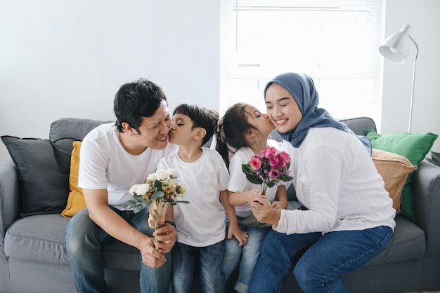 Zdjęcie dzieci całują rodziców i dają kwiaty syn całuje ojca i córkę całują matkę w domu