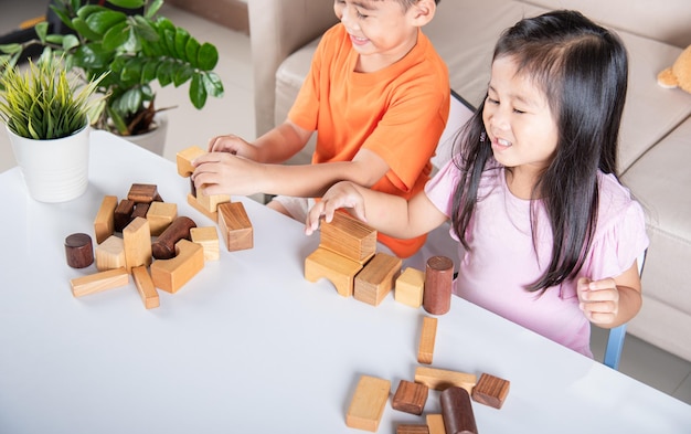 Dzieci chłopiec i dziewczynka bawią się drewnianymi klockami konstruktora