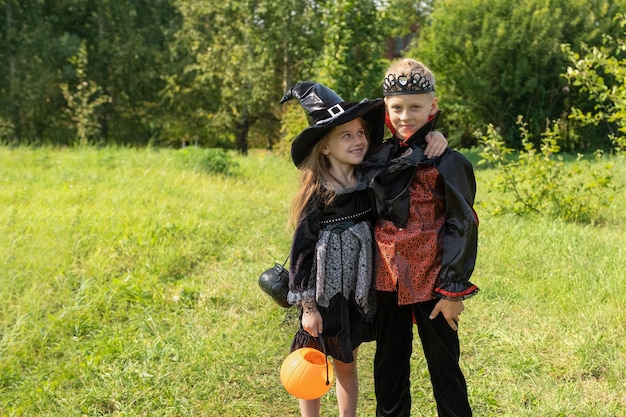 Dzieci chłopiec i dziewczynka w karnawałowych strojach czarownic i Drakuli na ulicy cieszą się świątecznym halloweenowym kapeluszem czarownicy Happy kids Vampire jackolantern Jesień Październik Wszystkich Świętych39 Dzień