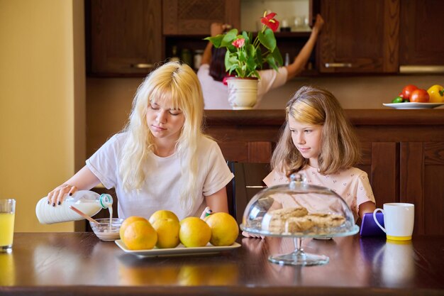 Dzieci dwie siostry jedzą w domu w kuchni