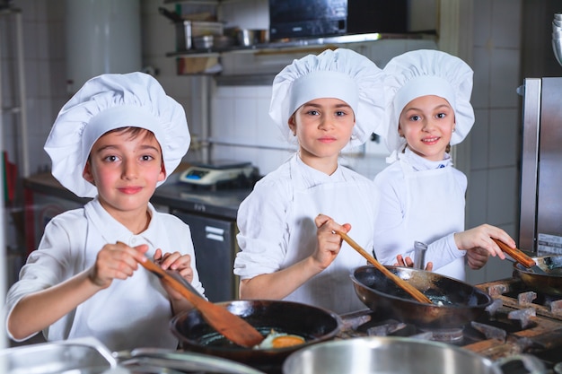 Zdjęcie dzieci gotują obiad w kuchni restauracji.