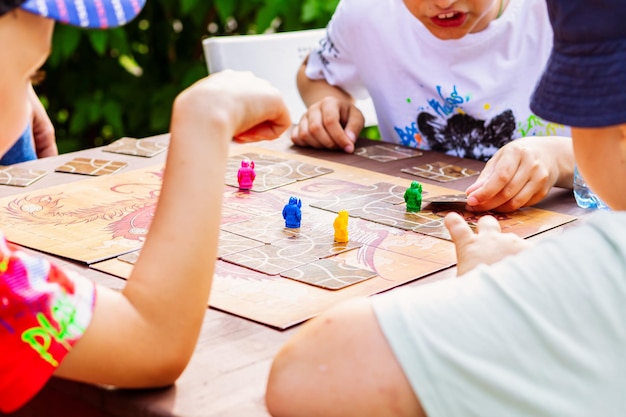 Dzieci grają w grę planszową podobną do Tsuro w letnim ogrodzie na świeżym powietrzu Noc gier zbliżeniowych z przyjaciółmi