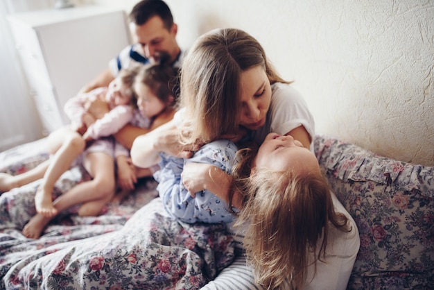 Dzieci I Rodzice Odpoczywają Rano W łóżku. Dzieci Oddają Się, Przytulają. Bliźnięta. Drzewa Córki.