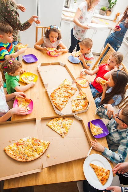 Dzieci jedzące pizzę przy stole, widok z góry