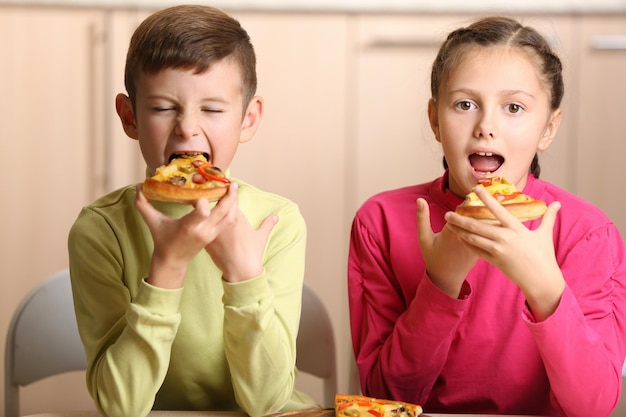 Dzieci jedzące pizzę w domu