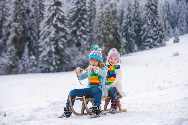 Dzieci na sankach jeżdżących na sankach dzieci syn i córka bawią się w śniegu zimą zabawa na świeżym powietrzu dla dzieci