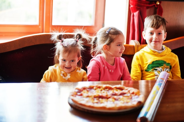 Dzieci na urodziny siedzą przy stole i jedzą pizzę