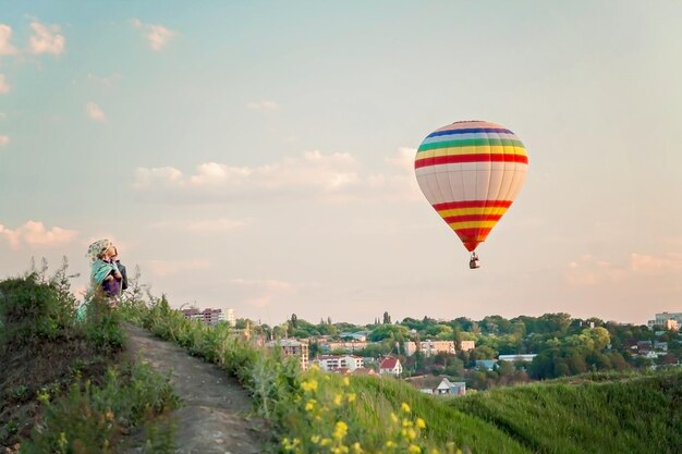 Dzieci na wzgórzu patrzące na balon na ogrzane powietrze