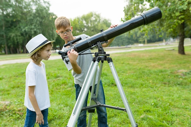 Dzieci nastolatki w parku patrząc przez teleskop