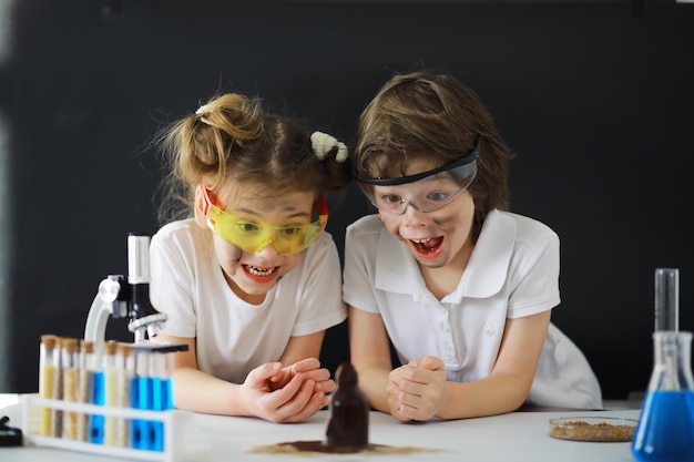 Dzieci-naukowcy Uczniowie w laboratorium przeprowadzają eksperymenty Chłopiec i dziewczynka eksperymentują pod mikroskopem