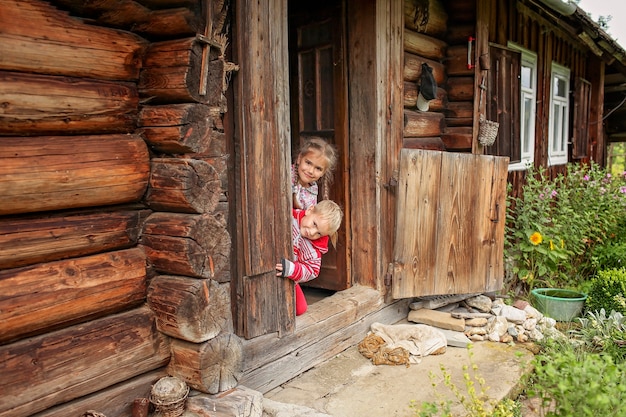 Dzieci Odpoczywające Na Progu Starego Drewnianego Domu Podczas Letnich Wakacji, Ekologiczna Koncepcja Podróży