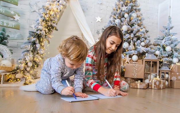 Dzieci piszą list do Świętego Mikołaja pod drzewem Selektywna ostrość