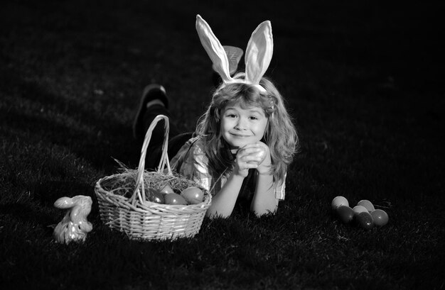 Dzieci polujące na jaja wielkanocne w parku leżące na trawie uroczy królik chłopiec z króliczymi uszami