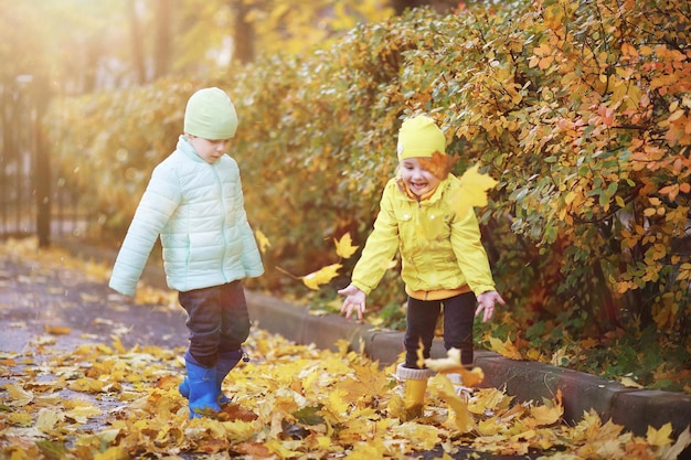 Dzieci spacerują po jesiennym parku jesienią