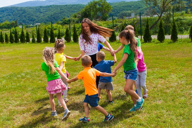 Dzieci Tańczą Trzymając Się Za Ręce W Kręgu Na świeżym Powietrzu Podczas Odpoczynku, Jasny Letni Dzień