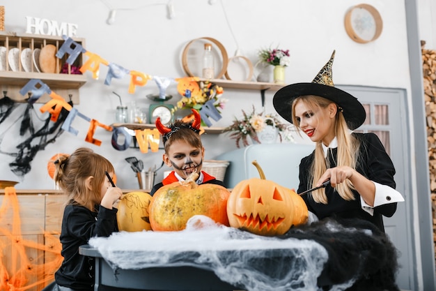 Dzieci ubrane w straszne kostiumy malują pomarańczowe dynie. Koncepcja Halloween. Wysokiej jakości zdjęcie