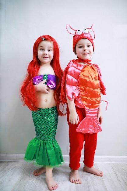 Zdjęcie dzieci w eleganckich kostiumach karnawałowych na prostym tle. kostium bajkowych stworzeń morskich. syrenka i krab. brat i siostra.