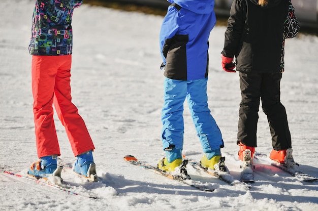 Dzieci w kombinezonach narciarskich jeżdżą na nartach po śniegu