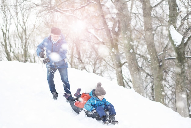 Dzieci w parku zimą. Dzieci bawią się śniegiem na placu zabaw. Rzeźbią bałwany i zjeżdżają ze wzgórz.