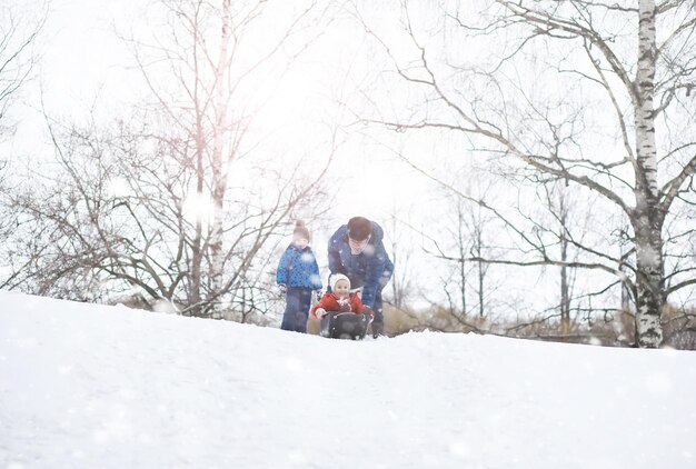 Dzieci W Parku Zimą. Dzieci Bawią Się śniegiem Na Placu Zabaw. Rzeźbią Bałwany I Zjeżdżają Ze Wzgórz.