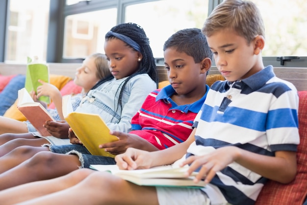 Dzieci w szkole siedzi na kanapie i czyta książkę w bibliotece
