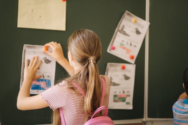 Dzieci w szkole stoją przy tablicy. Szkoła Podstawowa. Edukacja