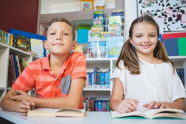 Dzieci w wieku szkolnym czytając książkę w bibliotece