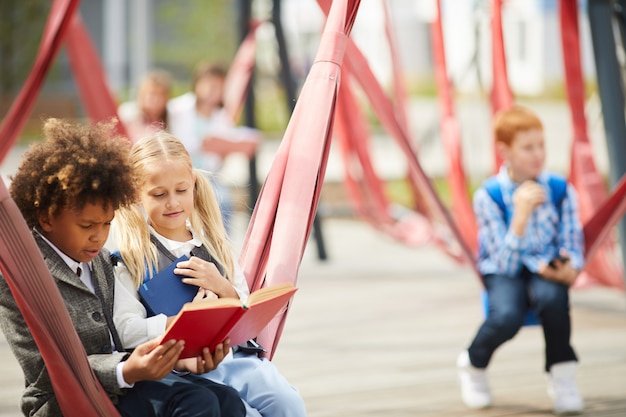Dzieci w wieku szkolnym, czytając książki na zewnątrz