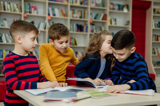 Dzieci w wieku szkolnym w bibliotece czytają książki, odrabiają lekcje, przygotowują szkolny projekt na lekcje