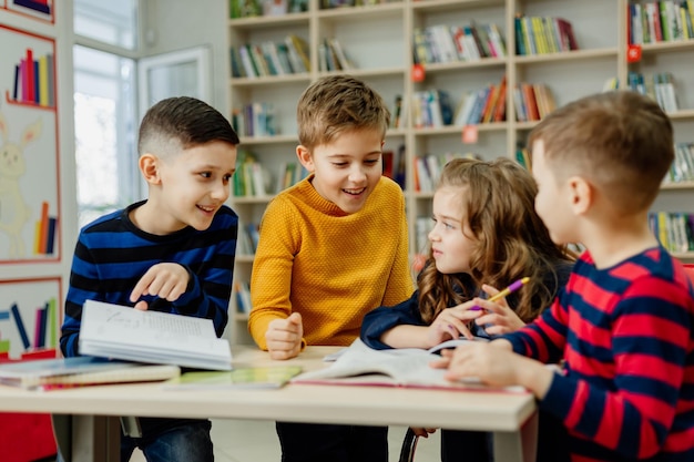 Dzieci w wieku szkolnym w bibliotece czytają książki, odrabiają lekcje, przygotowują szkolny projekt na lekcje