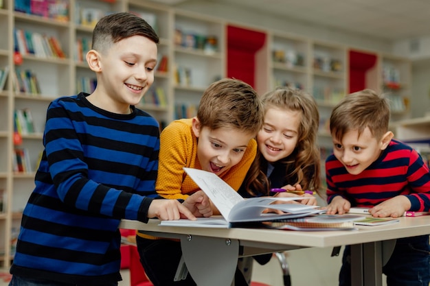 Dzieci w wieku szkolnym w bibliotece czytają książki, odrabiają lekcje, przygotowują szkolny projekt na lekcje