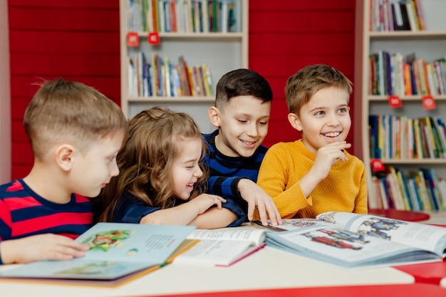 Dzieci w wieku szkolnym w bibliotece czytają książki, odrabiają lekcje, przygotowują szkolny projekt na lekcje