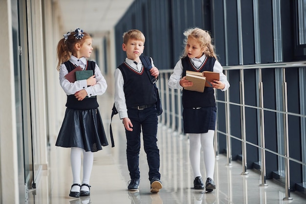 Dzieci w wieku szkolnym w mundurkach razem na korytarzu Koncepcja edukacji