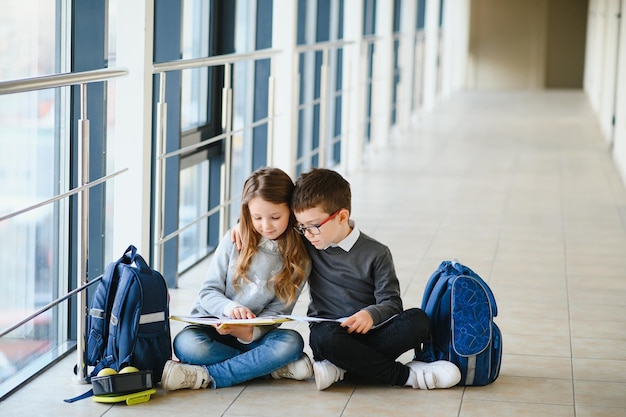 Dzieci w wieku szkolnym z książkami razem na korytarzu Koncepcja edukacji