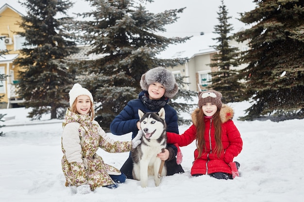 Dzieci wychodzą i bawią się z psem husky zimą