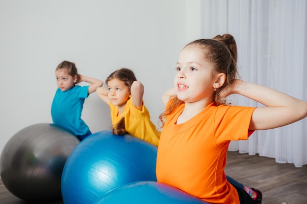Zdjęcie dzieci wykonujące ćwiczenia fizyczne na dużych piłkach fitball