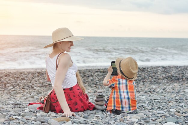 Dzieciak fotografuje swoją matkę przez telefon na wybrzeżu morza