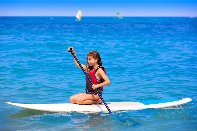 Dzieciak paddle surfować surfer dziewczyna z rzędu na plaży