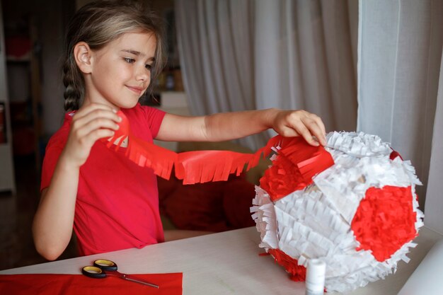 Zdjęcie dzieciak robi pinatę z kartonu z używanego pudełka i kolorowe papierowe dekoracje zrób to sam na przyjęciu urodzinowym