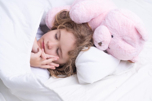Dzieciak śpi z zabawkowym misiem w łóżku na dzień dziecko śpi drzemiący cute kid śpi w łóżku sleepi