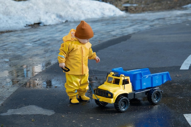 Zdjęcie dzieciak toczy zabawkową ciężarówką przez kałuże