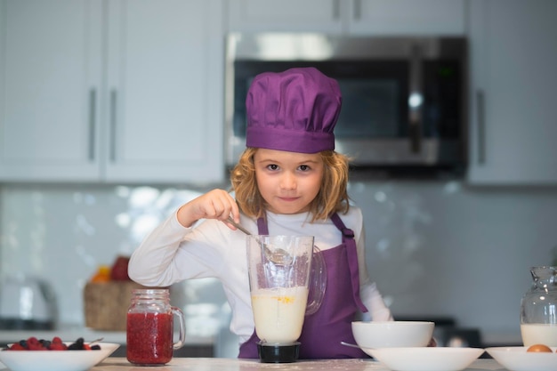 Dzieciak w czapce szefa kuchni i fartuchu dzieci przygotowują ciasto do pieczenia ciasteczek w kuchni
