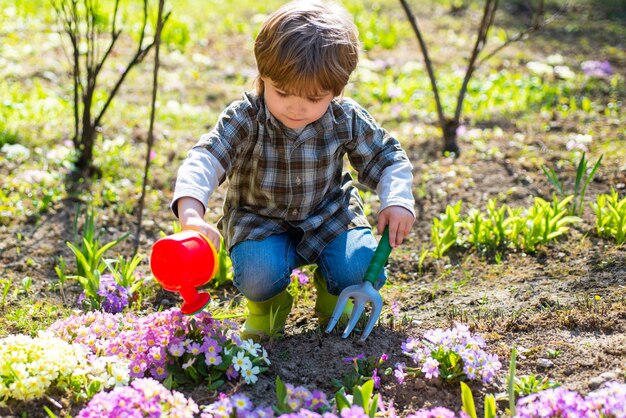 Dzieciak z łopatą i konewką Profesjonalny ogrodnik w pracy Mały ogrodnik ogrodniczy w przydomowym ogródku