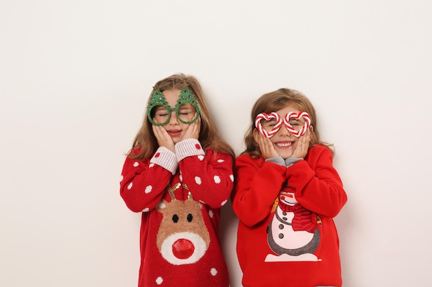 Dzieciaki w świątecznych swetrach i świątecznych okularach na białym tle