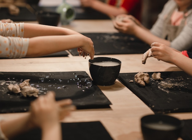 Dzieciaki w warsztacie garncarskim tworzące różne rzeczy z gliny. Warsztaty garncarskie.