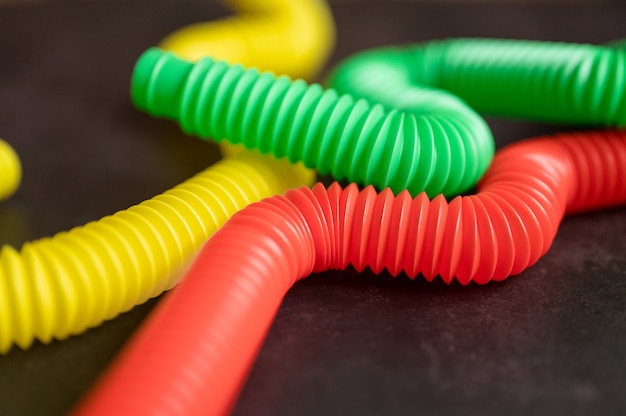 Dziecięca Zabawka Antystresowa Sensoryczna Pop Rurka Plastikowa Fidget Push Na Czarnym Tle Stołu Lub Podłogi. Małe Zabawki Dla Dzieci Poptube Wielokolorowy Odcień Jasny Kolor, Trend 2021 Rok