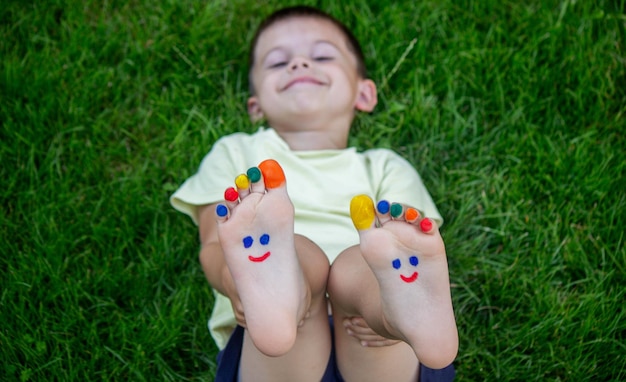 Dziecięce nogi z wzorem wykonanym z farb uśmiechają się na zielonej trawie