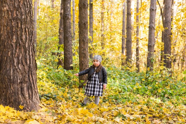 Dzieciństwo, jesień, koncepcja ludzi - dziecko dziewczynka spaceru w jesiennych liściach.
